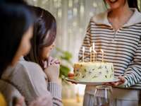 Woman bringing birthday cake with lighted candles to sister-in-law