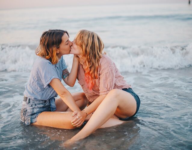 Couple shares a kiss on the beach for their summer engagement photo session. 