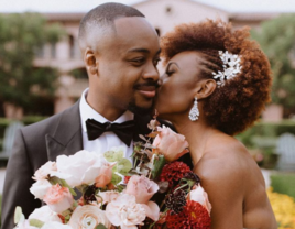 Couple holding bouquet and sharing kiss