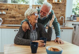 Elderly couple laughing together while having tea