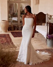 Bride in a strapless floral lace wedding dress posing in a rustic Mediterranean-style villa.