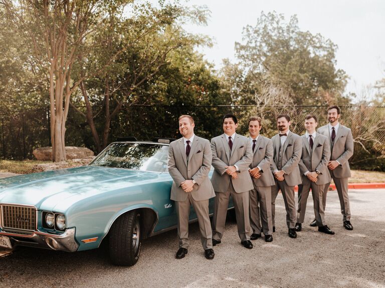 Groomsmen standing beside a vintage car