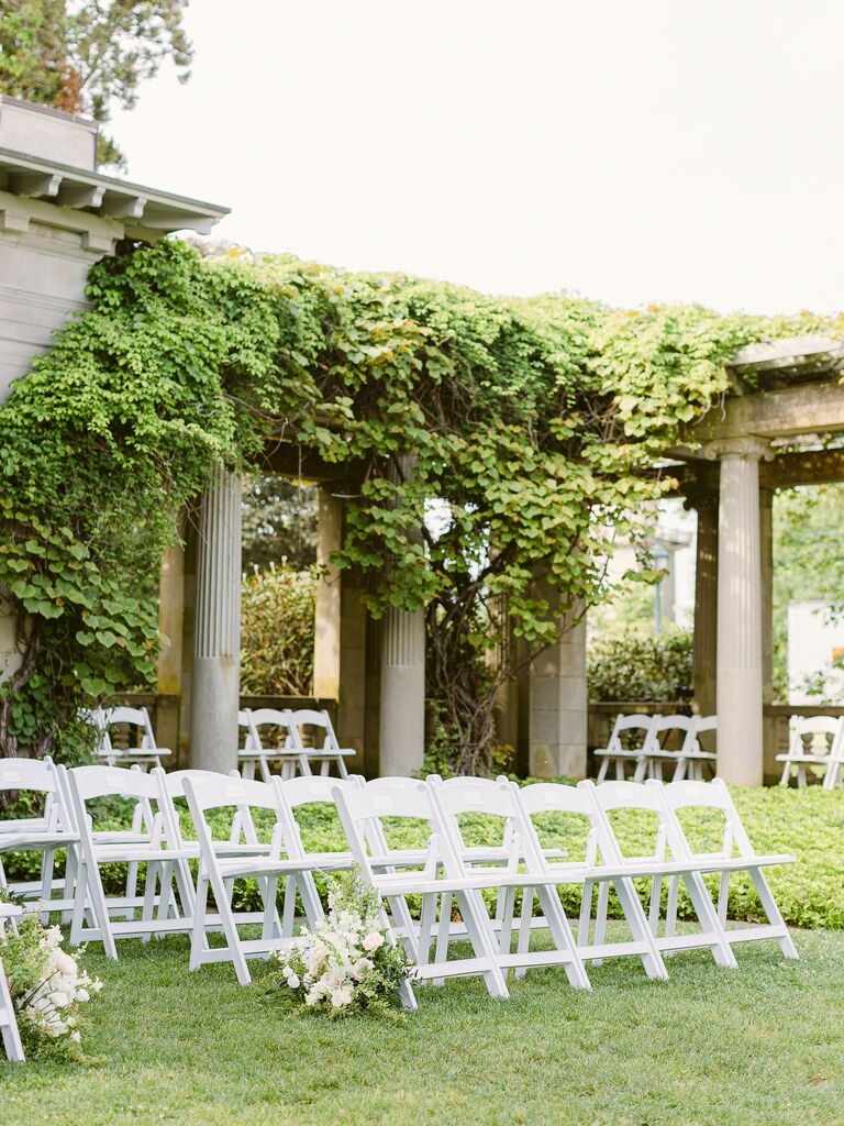 ceremony chairs lined up at garden wedding venue with grecian-style pillars covered in ivy