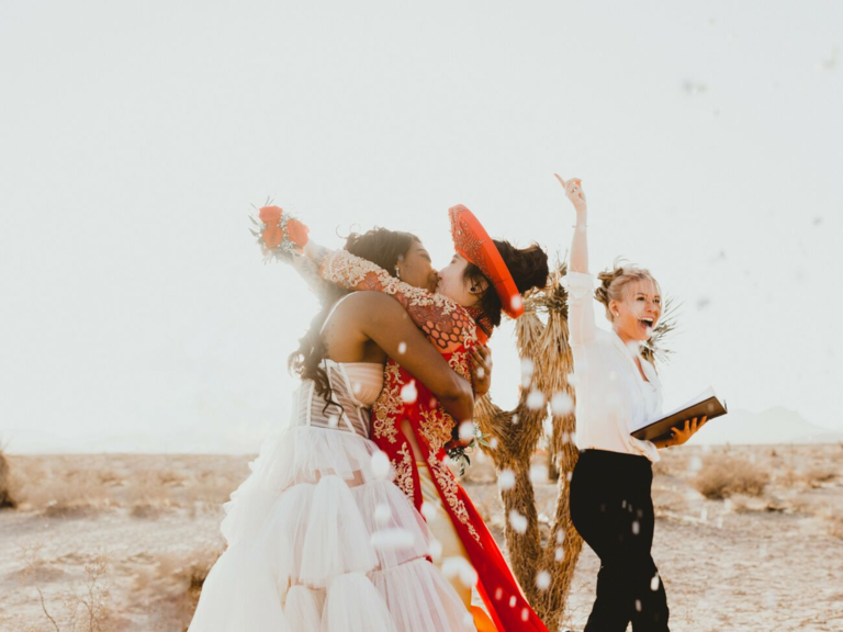 Couple kissing at the altar with officiant cheering for them