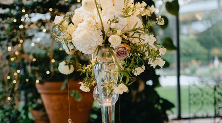 Greenery hanging in the tent at Green Acres with chandeliers and tall  flower centerpieces - Floral V Designs