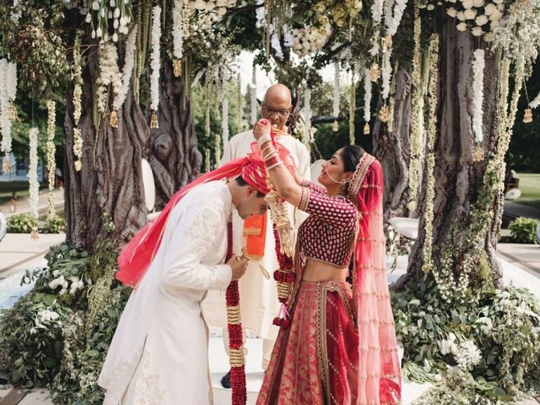 bride putting floral garland on groom during Indian wedding ceremony