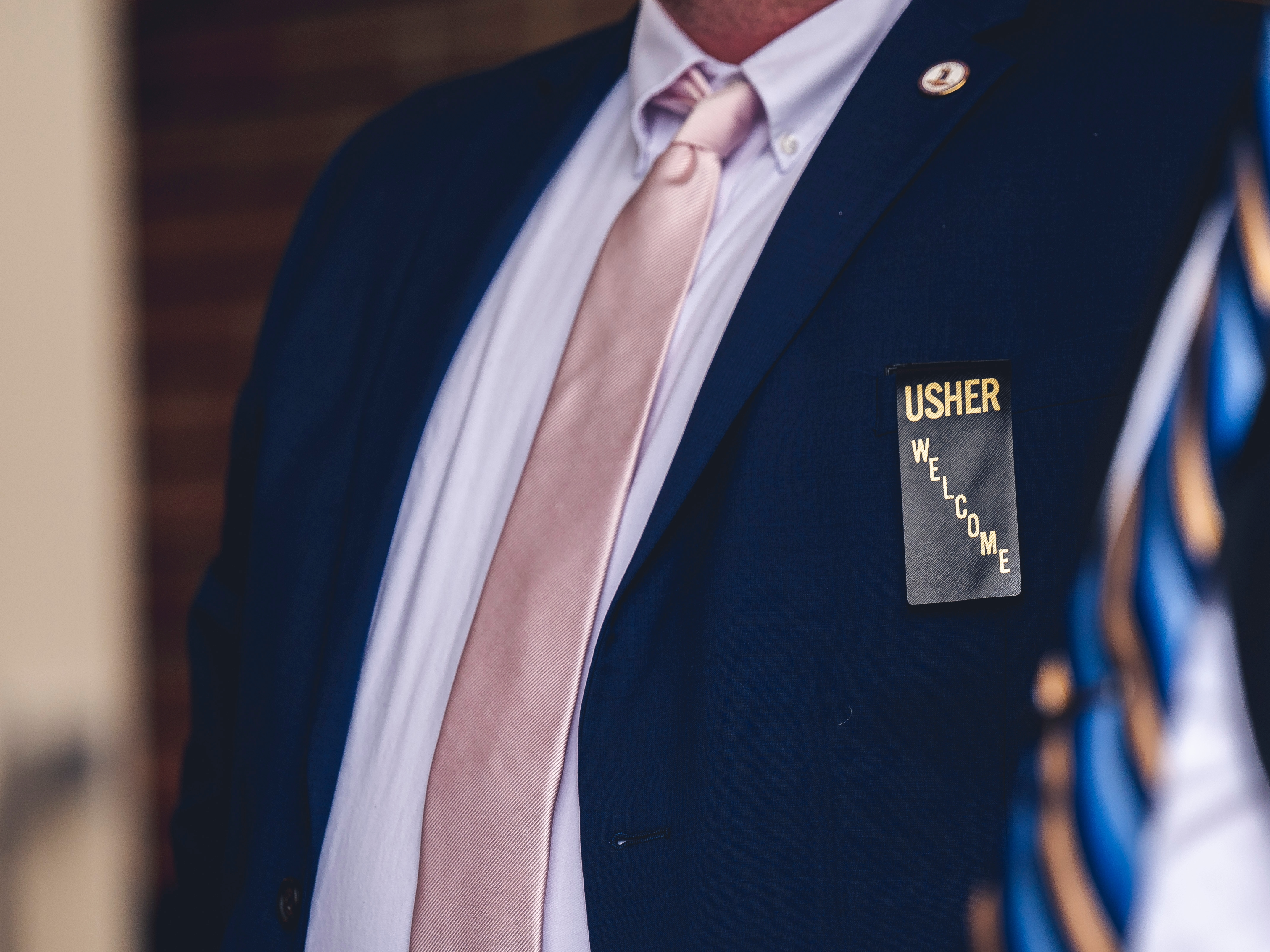 Man in blue suit with usher badge
