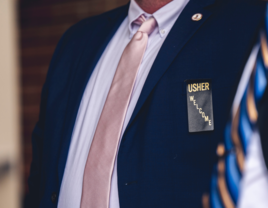 Man in blue suit with usher badge