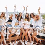 group of bridesmaids and bride posing next to bride to be balloons wearing matching outfits