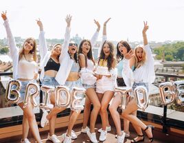 group of bridesmaids and bride posing next to bride to be balloons wearing matching outfits