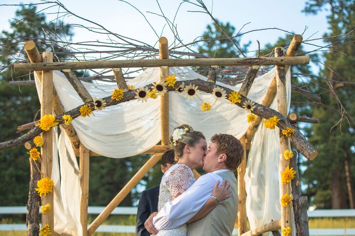 Carlen and Tommy exchanged vows (and kisses) under a rustic unfinished wooden wedding arbor. The arch was adorned with yellow sunflowers and spider mums for a romantic pop of color that matched the gorgeous ranch venue in Indian Hills, Colorado.