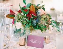 wedding centerpiece with table number written in elegant gold calligraphy on burgundy paper