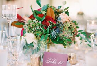 wedding centerpiece with table number written in elegant gold calligraphy on burgundy paper