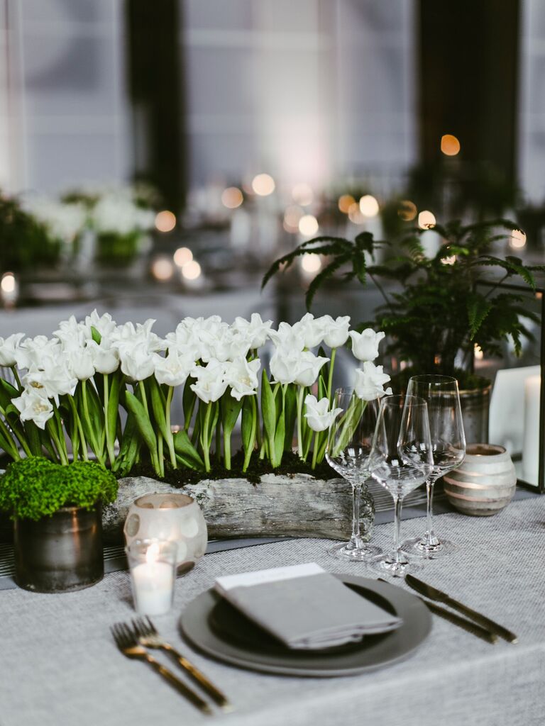 low wedding centerpiece with white long-stem tulips standing up in wooden trough