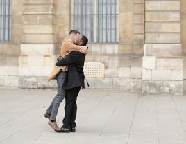 two men smile and embrace as a couple