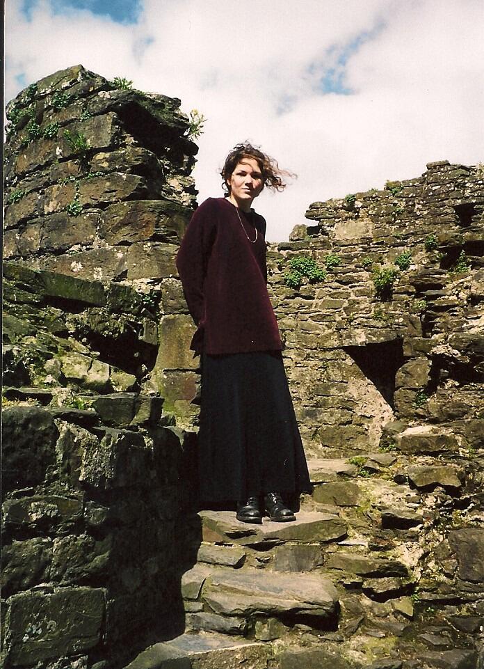 A young Angela on a castle wall in Wales while studying abroad in the UK 
