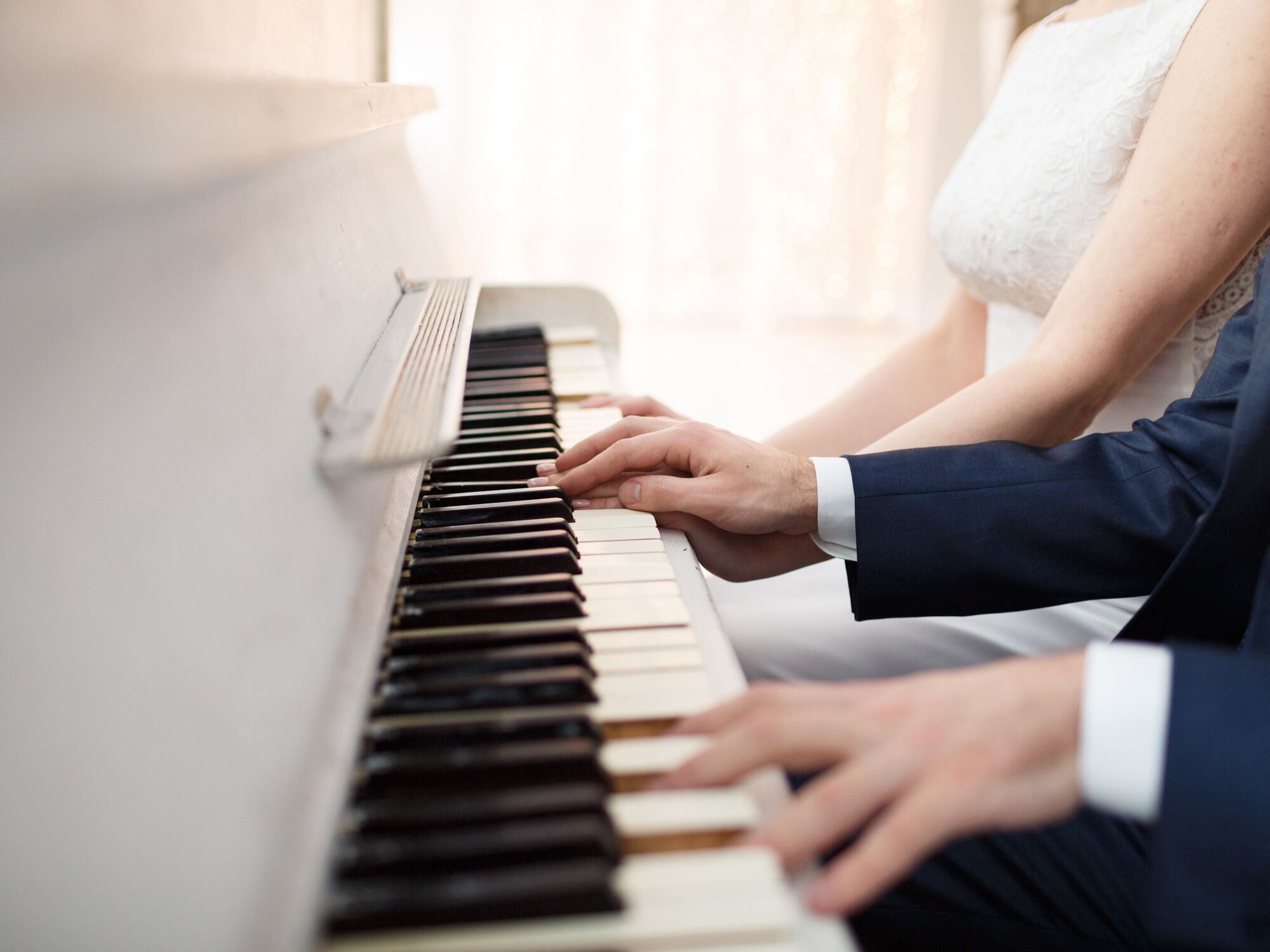 bride and groom play white piano