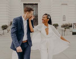 groom kissing bride's hand as they walk together