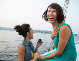 Woman proposing to partner on boat while smiling and laughing