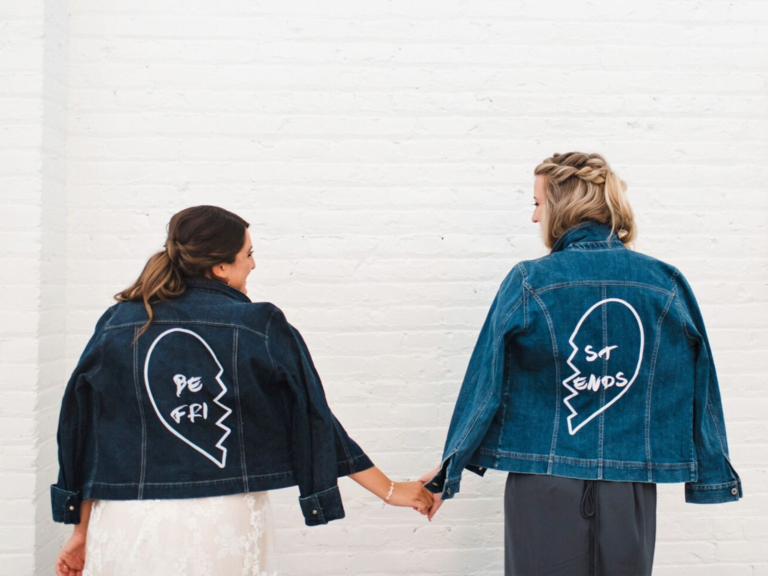 Bride and maid of honor holding hands wearing matching denim jackets