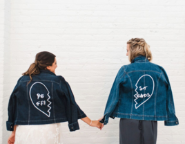 Bride and maid of honor holding hands wearing matching denim jackets