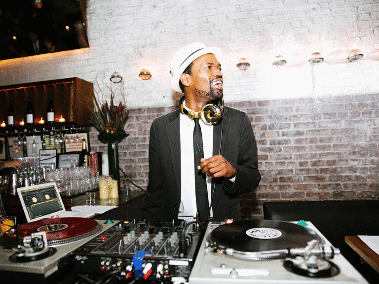 DJ smiling while playing music at a wedding.
