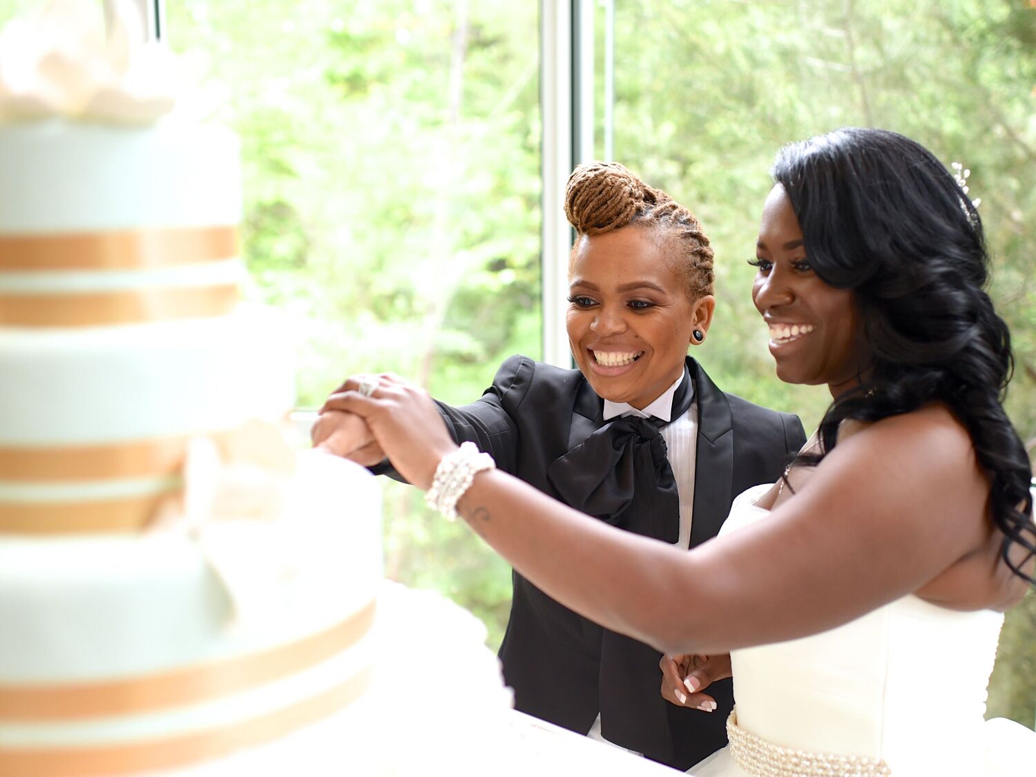 Couple cutting their wedding cake in front of guests during wedding reception.