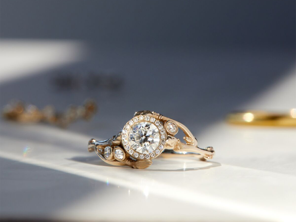 Round center diamond with diamond halo on gold asymmetrical band with three diamonds on sides