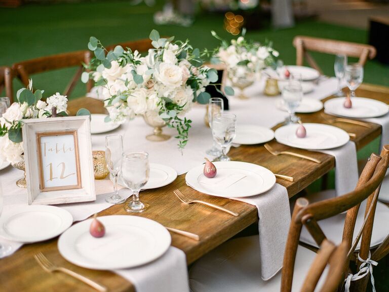 elegant rustic wedding tablescape with low centerpieces of white flowers and greenery