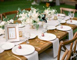 elegant rustic wedding tablescape with low centerpieces of white flowers and greenery