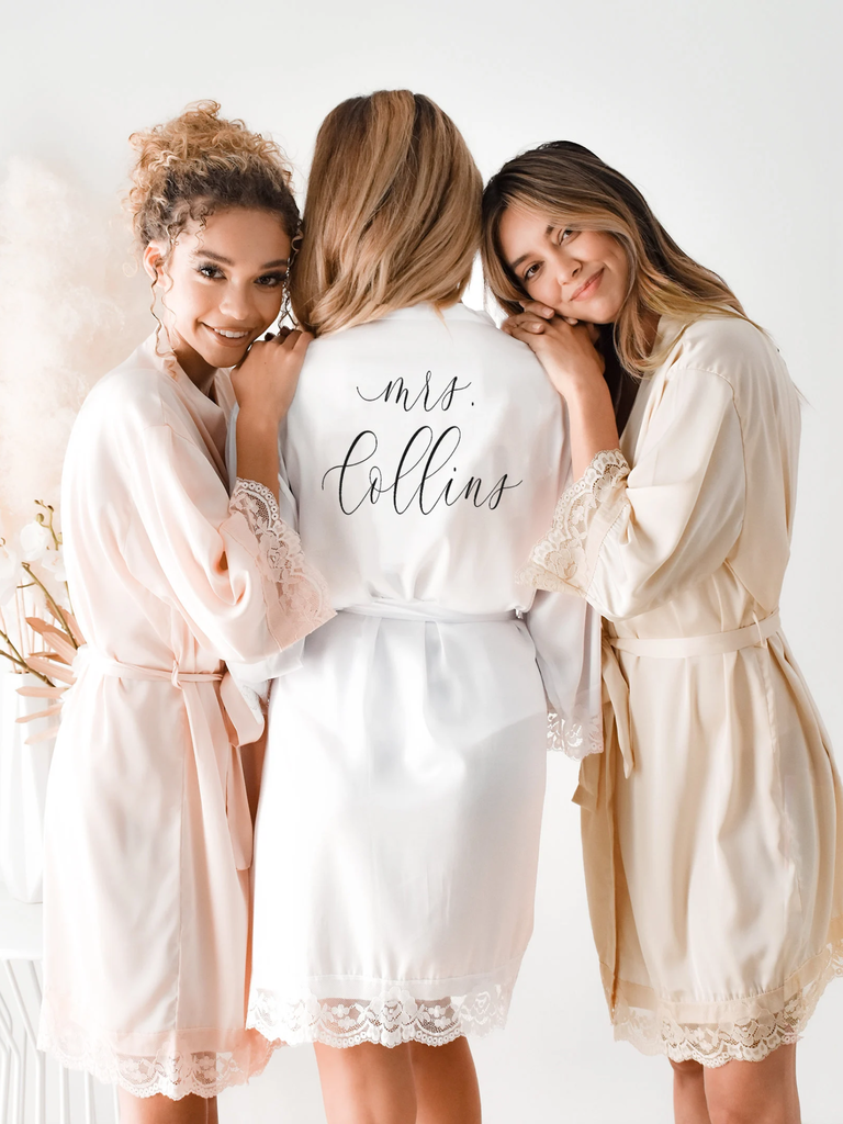Three models pose in their robes, showing off the personalized backs of the garments.