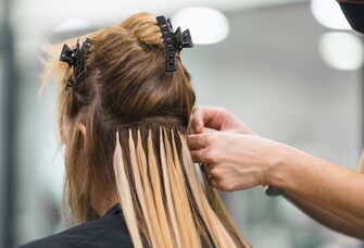 Hairstylist putting extensions in bride's hair