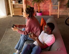 Couple sitting on couch playing video game together