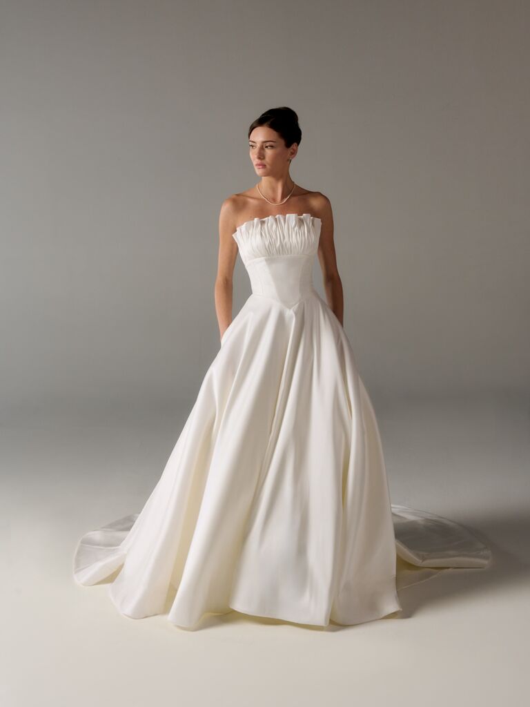 Strapless ball gown wedding dress by Poeza with ruffled neckline and simple skirt