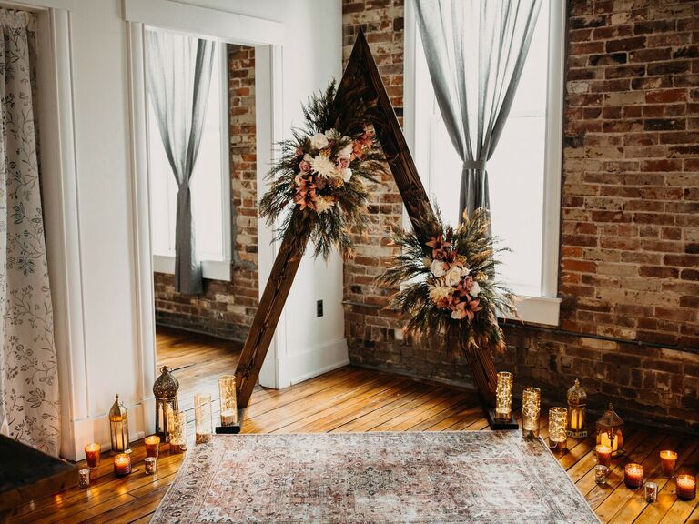 Wood triangle arch surrounded by candles in industrial venue with exposed brick