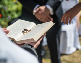 Two wedding rings rest on the Bible at a wedding