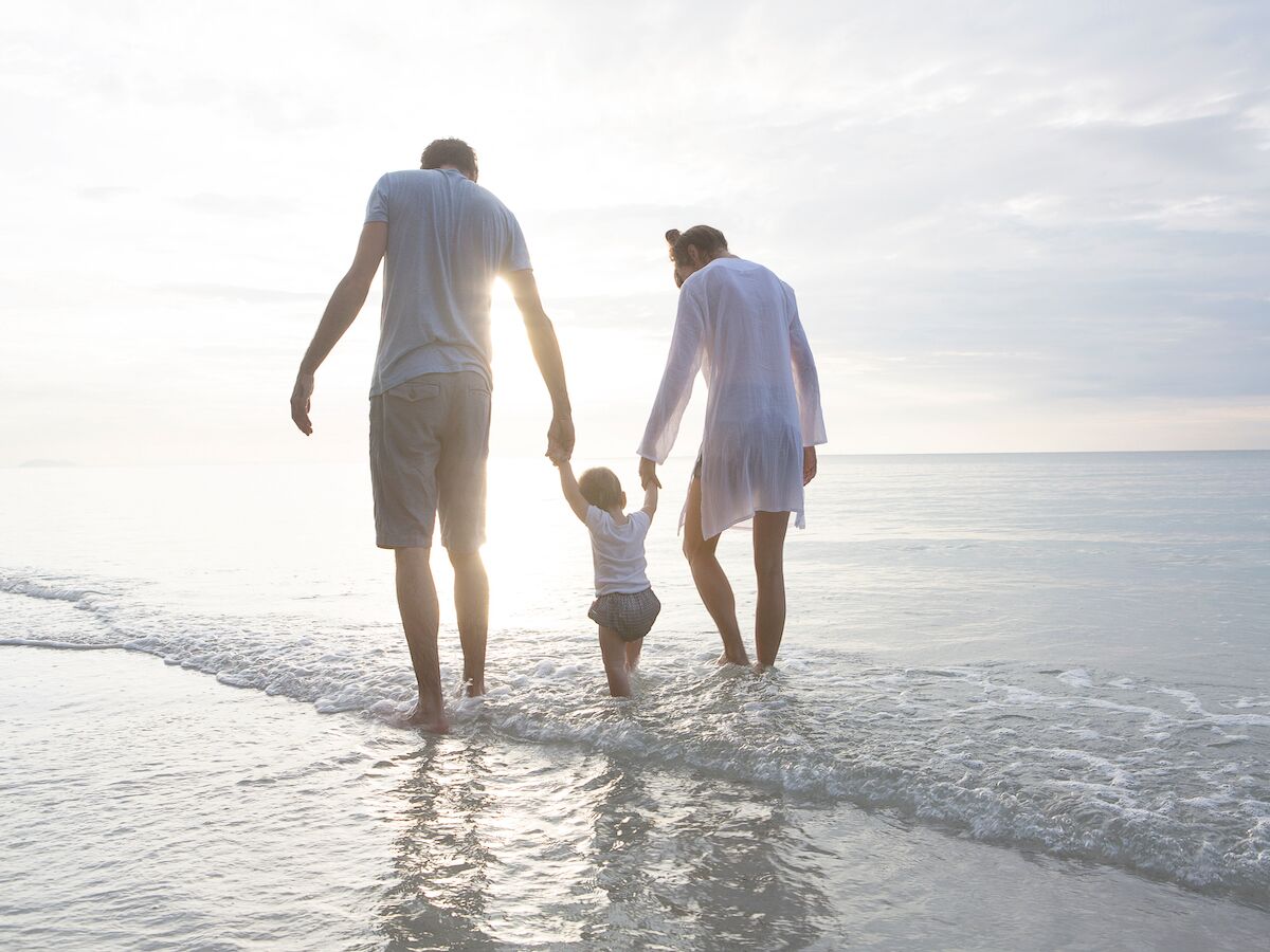 Family walking along the shore on a beach.