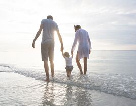 Family walking along the shore on a beach.