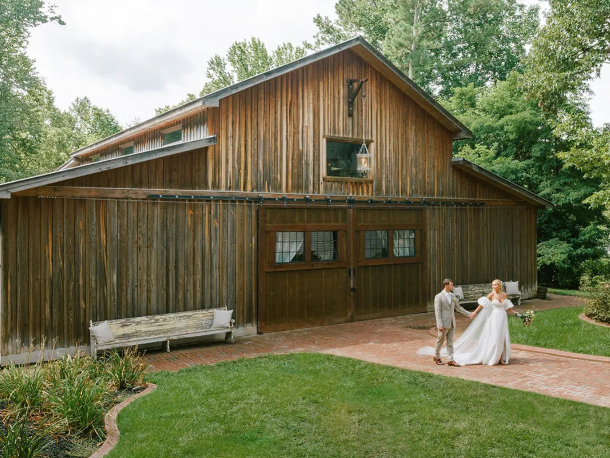 Bride and groom holding hands in front of barn at The Wheeler House and Barn affordable wedding venue in Ball Ground, Georgia