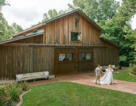 Bride and groom holding hands in front of barn at The Wheeler House and Barn affordable wedding venue in Ball Ground, Georgia