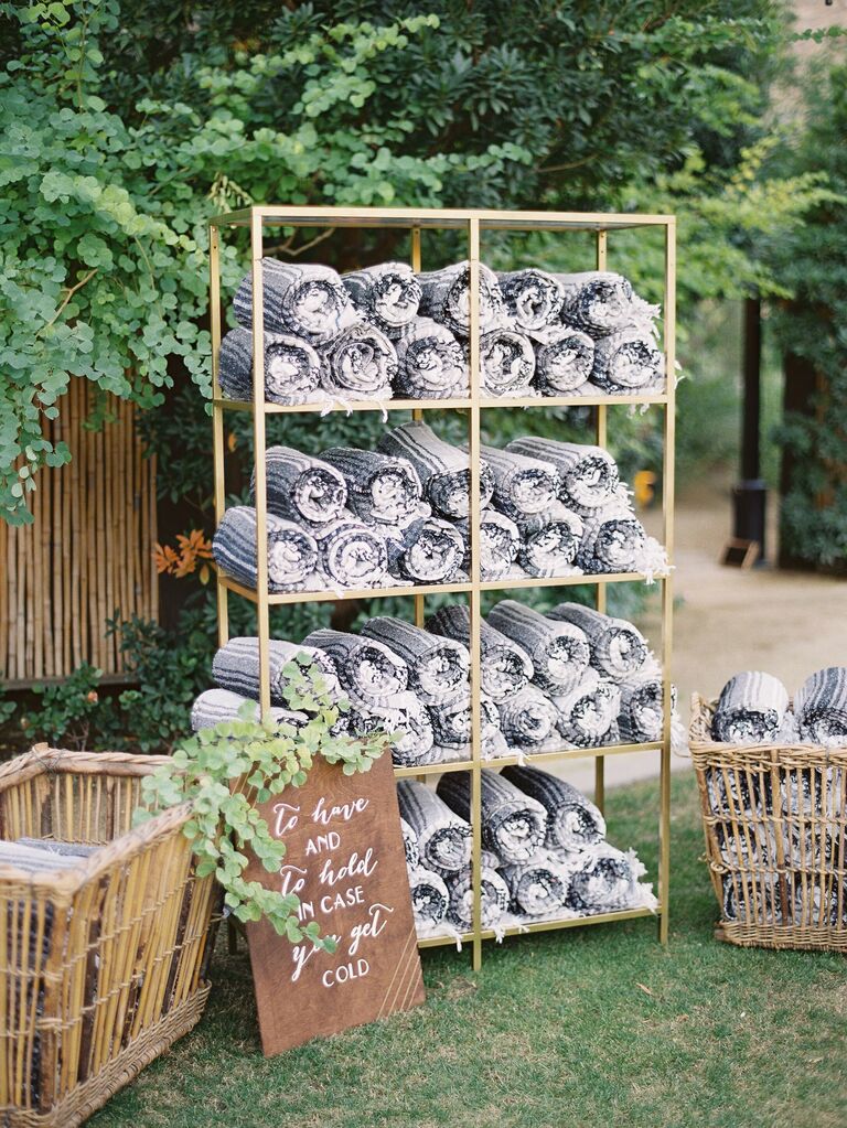 wedding favor display with rolled up blankets stacked on gold metal shelves