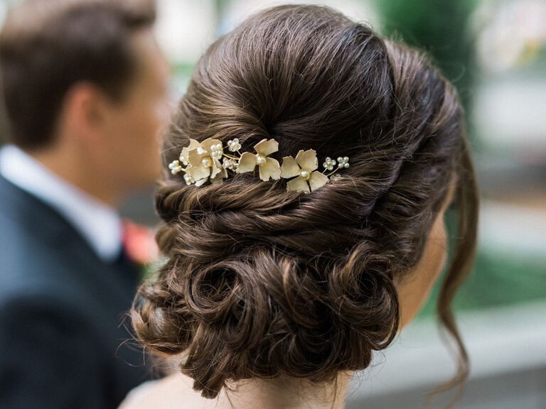 Bride wears her hair in a curled, elegant updo. 