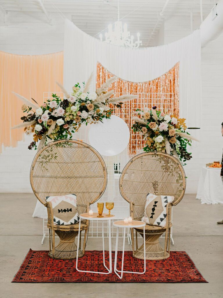 two peacock chairs with end tables, kilim rug and hanging pampas grass floral installation