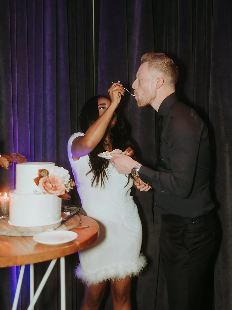 A couple feed wedding cake to each other