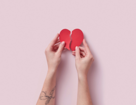 Person's hands holding two broken heart pieces together, falling in love after divorce