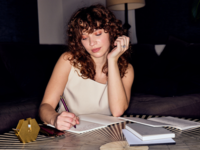 Woman writing in journal with planning supplies around her, How to plan a neurodivergent wedding