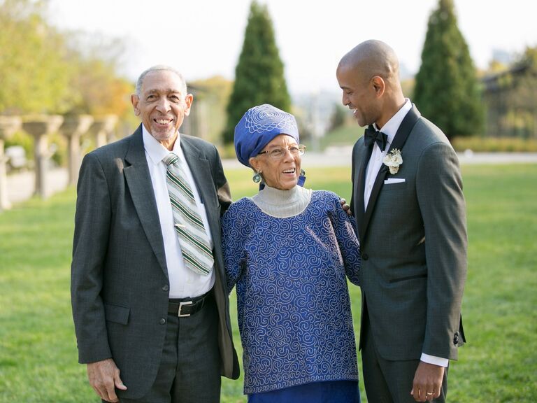 Groom poses with his parents, ultimate guide to father of the groom attire. 