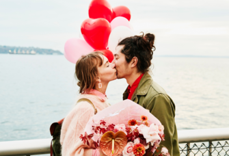 Couple kissing on boardwalk holding heart shaped balloons