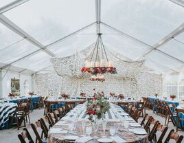 Wedding reception inside a clear enclosed event tent with a hanging chandleier and decor