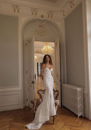 Strapless mermaid gown highlights the figure with intricate lace from the bust to the hips. The structured bodice features a sweetheart neckline and detailed corset, enhancing the waist. A trail of shimmering sequins runs throughout the dress, while it’s fitted silhouette flares out into a graceful train.